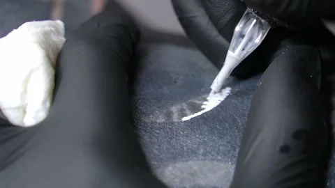 Close-up of a tattoo machine needle with white paint paints the skin. Close-up Stock Footage 275246344