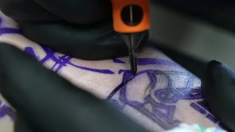 Close-up of a tattoo machine needle with white paint paints the skin. Close-up Stock Footage 275246375