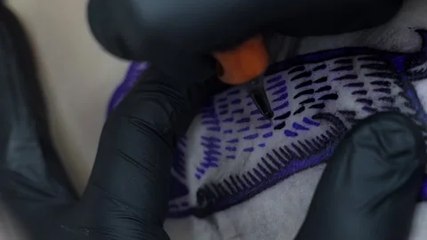 Close-up of a tattoo machine needle with white paint paints the skin. Close-up Stock Footage 275246562