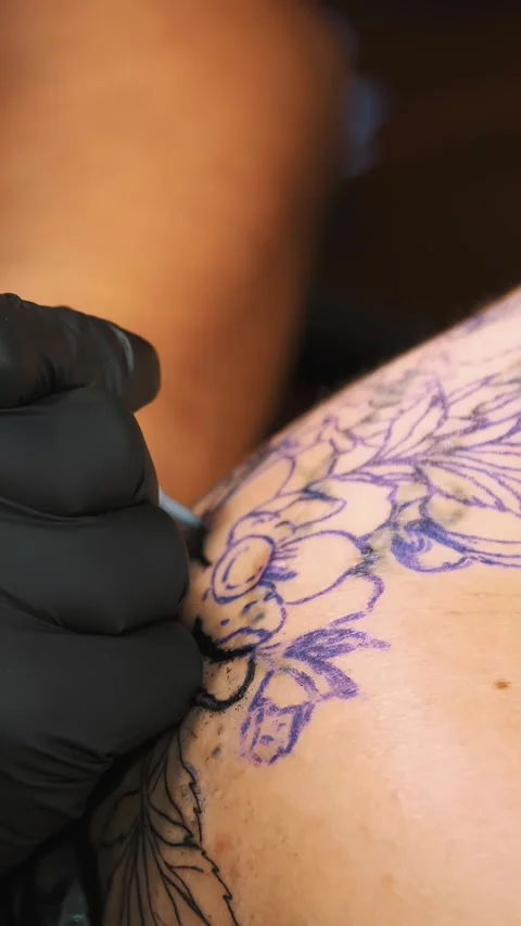 Close-up, in a tattoo salon , a specialist is doing a tattoo on woman's back, Stock Footage 307925014