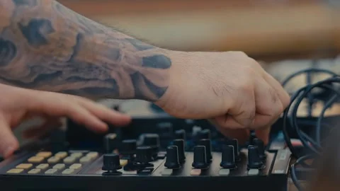 Close Up of Tattooed DJ Hands Adjusting Knobs and Faders on Sound Controller Stock Footage 343326340