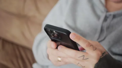 Close-up of tattooed hands using a smartphone while texting or browsing... Stock Footage 318177948