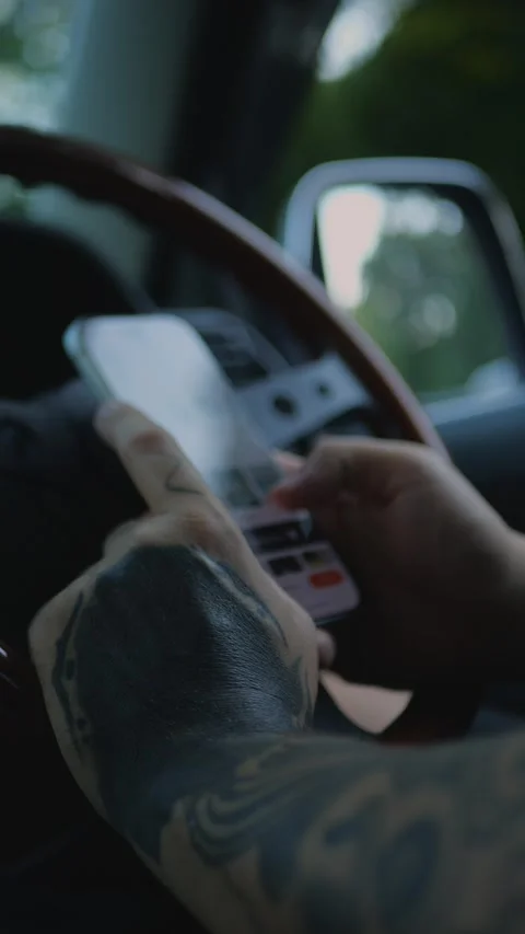 Close-up of tattooed hands using a smartphone inside a car, with the steering... Stock Footage 341613201