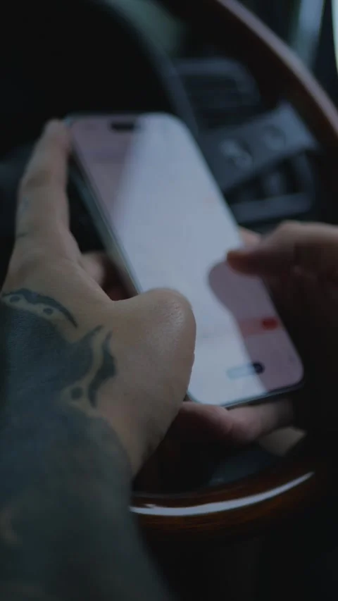 Close-up of tattooed hands using a smartphone inside a car... 库存影片 341613207