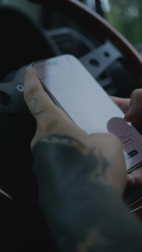 Close-up of tattooed hands using a smartphone inside a car, with the... Stock Footage 341613216