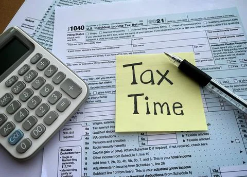 Close up on tax time text on sticky note with 1040 tax form, pen and calculator Stock Photos
