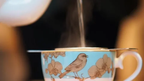 Close Up Of Tea Being Poured Into A Beautiful Blue Teacup, UK Stock Footage 221272943