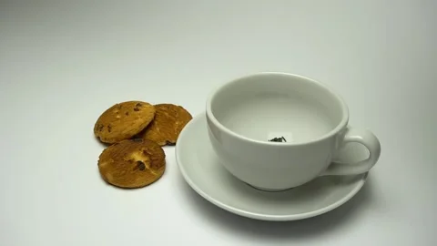 Close up of tea being poured into cup with cookies. Zoom in Stock Footage 85642938