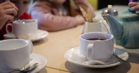 Close-up of tea being poured into cups in bustling cafe with eager guests Stock Footage 311586535