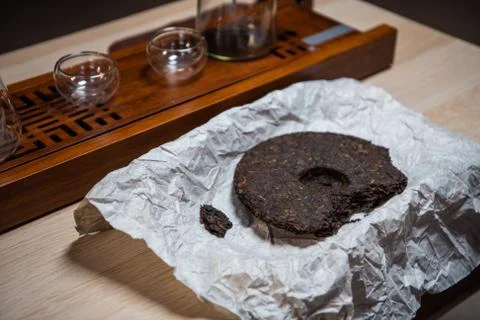 Close-up of a tea cake of real eastern pu-erh tea on the table in a paper Foto stock