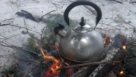Close up of tea kettle on open fire in wilderness in winter with snow Stock Footage 121220442