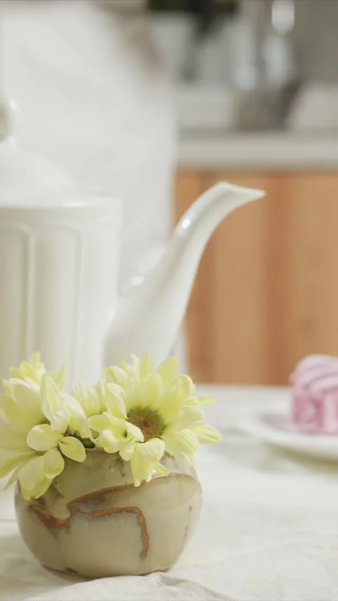 Close up tea pot pours liquid into glasses table set yellow floral vase pink Stock Footage 344420141