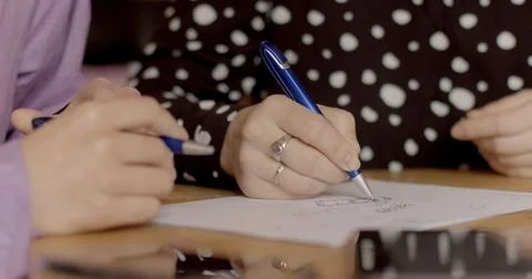 Close-up teacher explains task to student, draws with pen on paper. No face. Stock Photos