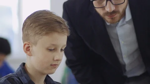 Close-up of a teacher helping his student understand programming and practice by Vidéo 111969394
