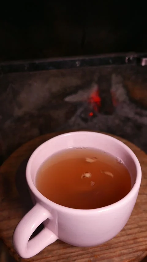 Close-up: a teacup by the fireplace. A cup of ginger tea with honey. Hot tea cup Stock Footage 335674818