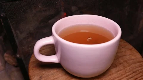 Close-up: a teacup by the fireplace. A cup of ginger tea with honey. Fireplace Stock Footage 335965747