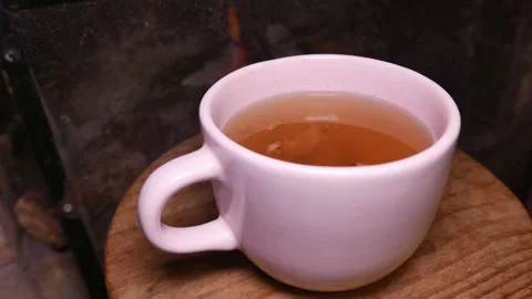 Close-up: teacup by the fireplace. Ginger tea with honey. Cup of tea on a table Stock Footage 340178207
