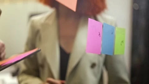 Close-up of team brainstorming with sticky notes on glass during planning 動画素材 315675254
