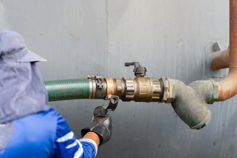 Close-up of a technician attaching a green flexible discharge hose to an in.. 스톡 사진