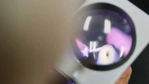 Close-up of a technician carefully sharpens a scalpel blade under a magnifying Stock Footage 303141546