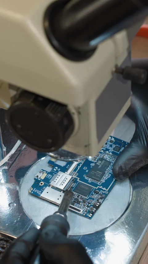 Close-Up of Technician Examining Circuit Board Under Microscope in Electronics Video stock 310490608
