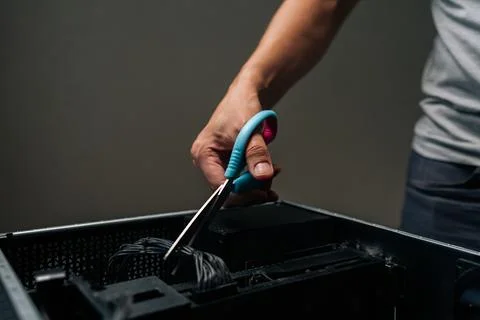 Close-up of technician hand using scissors to cut cable inside desktop computer Stock Photos