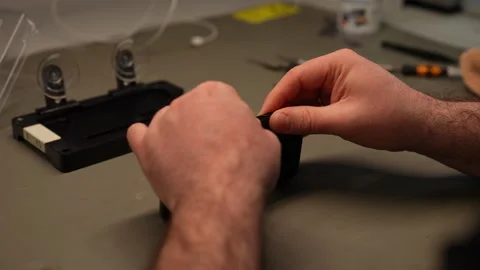 Close-up of technician hands assembling smartphone on workbench, showcasing Stock Footage 307831004