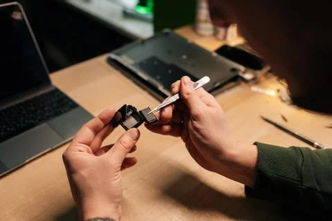 Close-up of technician hands carefully replacing smartwatch battery using Stock Photos