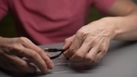 Close-up of technician hands comparing different charging connectors, analyzing Stock Footage 297631267