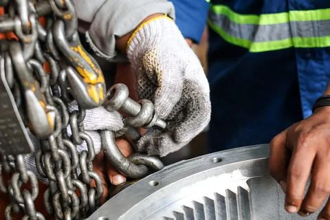 Close up of technician hands in gloves installing a heavy-duty steel shackle. Stock Photos