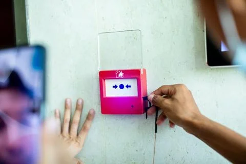 Close-up of technician hands installing and wiring a red fire alarm manual .. Stock Photos