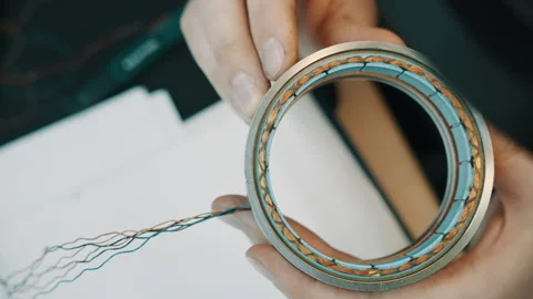 Close-up of a technician holding a circular stator coil with copper windings and Stock Footage 335861178