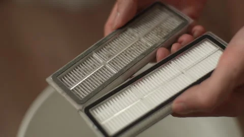 Close-up technician male comparing pristine and worn HEPA filter. Concept of Stock Footage 297625545