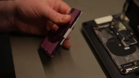 Close-up of technician removing adhesive strip from smartphone battery Stock Footage 306895667