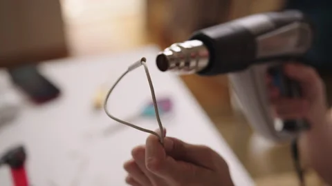 Close-up of technician using heat gun to repair damaged charging cable in Stock Footage 317541860
