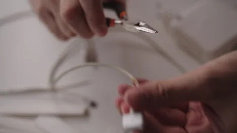 Close-up of technician using pliers to carefully repair damaged charging cable Stock Footage 317398279