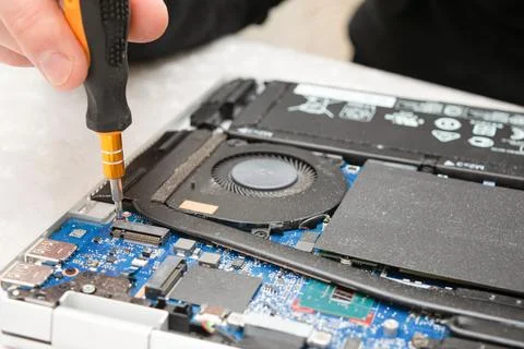 Close-up of a technician using a screwdriver to repair a laptop's internal .. Stock Photos