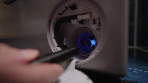 Close-up of technician using UV flashlight to inspect filter of washing machine Stock Footage 313298430