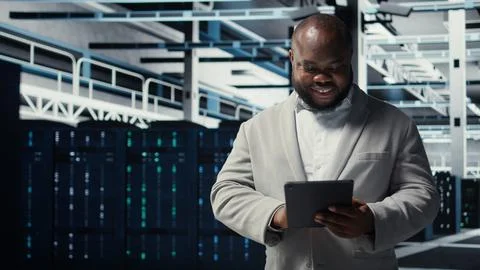 Close up of technician walking in data center, using tablet to check equipment Stock Photos