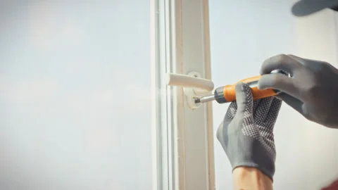 A close-up of a technicians gloved hands unscrewing plastic window fasteners Stockbeeldmateriaal 341490722