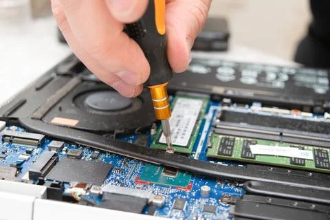 Close-up of a technician's hand using a screwdriver to install RAM in a lap.. Stock Photos