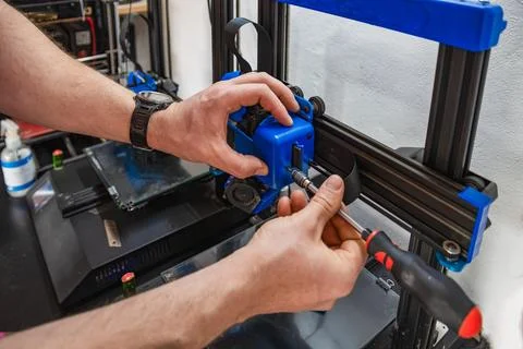 Close-up of technician's hands doing maintenance on 3D printer. Stock Photos