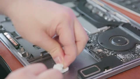 Close-up of a technician's hands wiping the battery seat in a laptop case with a Stock Footage 337828430