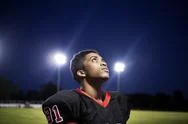 Close-Up Of Teenage American Football Player Looking Up At Illuminated Field Stock Photos