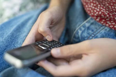 Close Up Of Teenage Girl Using Basic Dumbphone Push Button Mobile Phone For.. Stock Photos