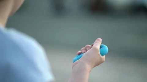 Close-up of a teenager's hand squeezing a blue ring hand grip exerciser Stock-Footage 337678380