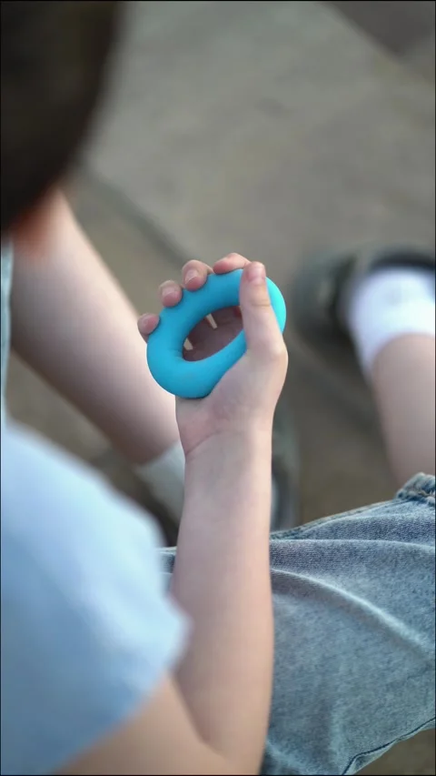 Close-up of a teenager's hand squeezing a blue ring hand grip exerciser Video stock 337678401