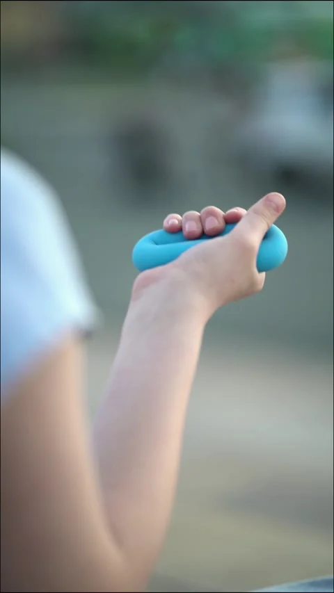 Close-up of a teenager's hand squeezing a blue ring hand grip exerciser Video stock 337678658