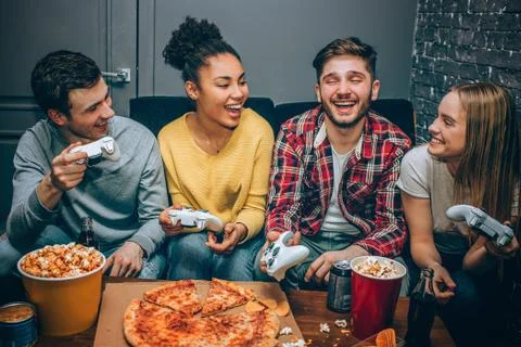 Close up of teens sitting on the sofa and playing game using console. This Stock Photos