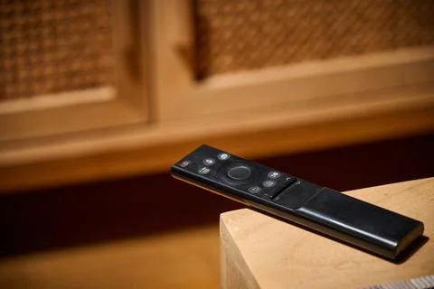 Close-up of a television remote control resting on a table. Stock Photos